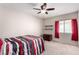 Bright bedroom with ceiling fan, window with red curtains, a bed, a dresser and decorative shelves at 8860 Hampton Green Ave, Las Vegas, NV 89129