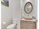 Stylish powder room with a vessel sink on a wood vanity and a uniquely framed oval mirror at 1223 Casa Palermo Circle Cir, Henderson, NV 89011