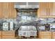 Close up of cooktop with decorative backsplash and beautiful countertops with natural wood cabinets at 1223 Casa Palermo Circle Cir, Henderson, NV 89011