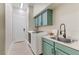 Well-lit laundry room with green cabinets, modern washer/dryer, and stainless steel sink at 1223 Casa Palermo Circle Cir, Henderson, NV 89011