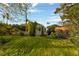 Green backyard featuring lush landscaping, mature trees, and a charming white picket fence at 2400 Llewellyn Dr, Las Vegas, NV 89102