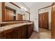 Bathroom with granite counters, dark wood cabinetry and tile floor with a door to walk-in closet at 2400 Llewellyn Dr, Las Vegas, NV 89102