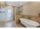 Bright bathroom featuring a soaking tub, a tiled shower, and natural light from the door to the outdoor space at 3361 Iberia St, Las Vegas, NV 89146