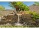Scenic waterfall feature with natural stone, lush greenery, and vibrant flowers at 40 Stonemark Dr, Henderson, NV 89052
