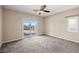 This spacious bedroom features plush carpeting, neutral walls, ceiling fan, and glass sliding door to patio at 5341 E La Campana Dr, Pahrump, NV 89061