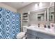 Well-lit bathroom featuring a single sink vanity, modern faucet, and shower-tub combination with patterned curtain at 5453 Palisades Quad Ave, Las Vegas, NV 89122