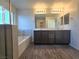 Bathroom featuring dual sinks, a tub, wood-style floors and a large mirror at 5817 Bonita Rose St, Las Vegas, NV 89113