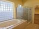 Bathroom with large glass block window above a soaking tub and glass enclosed shower in neutral tile at 601 Summer Mesa Dr, Las Vegas, NV 89144