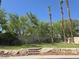 Landscaped front yard featuring lush lawn, mature trees, and a decorative retaining wall with stone and brick accents at 601 Summer Mesa Dr, Las Vegas, NV 89144