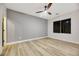 Well lit bedroom featuring a ceiling fan, wood flooring, gray walls and bright window at 62 Incline Village Ct, Henderson, NV 89074