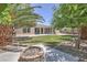 Landscaped backyard features a fire pit area, lush grass, and mature trees for a relaxing outdoor space at 6821 Sleepy Pine St, Las Vegas, NV 89130