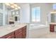 Bright bathroom featuring a soaking tub, double sinks, and large mirrors with vanity lighting at 6821 Sleepy Pine St, Las Vegas, NV 89130