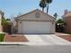 View of the two-car garage and driveway of a single-story home with low-maintenance desert landscaping at 7542 Mycroft Ct, Las Vegas, NV 89147