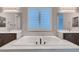 Luxurious bathroom featuring a soaking tub, dual vanities, and elegant lighting fixtures at 7966 W Ford Ave, Las Vegas, NV 89113