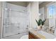 Clean bathroom showcasing a tub with sliding glass doors, granite countertop, vanity with sink, and window view at 8209 Chapelle Ct, Las Vegas, NV 89131