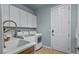Well-equipped laundry room with white cabinets, countertop sink, washer, dryer, and tiled floors at 8209 Chapelle Ct, Las Vegas, NV 89131