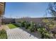 Well-maintained backyard with artificial turf, a wood deck, and lush landscaping along the brick wall at 9357 Aria Ridge Ave, Las Vegas, NV 89143