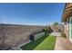 Neat backyard featuring artificial turf, a stone bed, and a modern planter against the brick wall at 9357 Aria Ridge Ave, Las Vegas, NV 89143