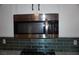 Close up of stainless steel microwave, teal backsplash, and white cabinets at , Las Vegas, NV 89130