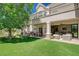 Spacious backyard with covered patio, outdoor kitchen, manicured lawn, and mature tree at 1266 Imperia Dr, Henderson, NV 89052