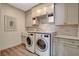 Bright laundry room with modern washer and dryer, tile backsplash, and plenty of storage at 1266 Imperia Dr, Henderson, NV 89052