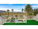 This lush backyard features a pool, mature palms, and stunning mountain views at 156 N Parawan St, Henderson, NV 89015