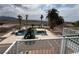 Backyard view of a sparkling blue pool with a sunning deck and several palm trees, set against a desert backdrop at 156 N Parawan St, Henderson, NV 89015