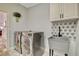 A laundry room featuring a utility sink with floral tile backsplash and modern washer and dryer at 1970 Del Font Ct, Las Vegas, NV 89117