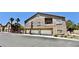 Low-angle view of a condominium building with garages, balconies, and palm trees under a clear blue sky at 2000 Gravel Hill St # 203, Las Vegas, NV 89117