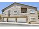 Condominium complex featuring stucco exterior, multiple garages, and a balcony against a clear blue sky at 2000 Gravel Hill St # 203, Las Vegas, NV 89117