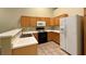 A well-lit kitchen has wooden cabinetry, white countertops, a tiled floor, and essential appliances at 2000 Gravel Hill St # 203, Las Vegas, NV 89117