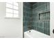 Bathroom featuring bathtub with shower, dark vertical tile and bronze fixtures at 2107 Fountain Springs Dr, Henderson, NV 89074