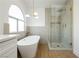 Modern bathroom featuring a soaking tub, frameless shower with beautiful tilework, and an arched window at 2107 Fountain Springs Dr, Henderson, NV 89074