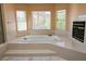 Bright bathroom featuring a large soaking tub with windows and a fireplace at 2208 Fiero Dr, Las Vegas, NV 89134