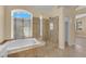 Bathroom features a glass shower, soaker tub, and travertine tile at 2417 Chestnut Hill St, Las Vegas, NV 89134