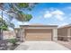 Home's front exterior with a large garage door and mature tree at 2432 Shady Hill Ave, Las Vegas, NV 89106