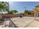 Large backyard with a concrete patio area, a brick-lined planter, and mature trees at 2621 Rainbow Glow St, North Las Vegas, NV 89030