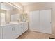 Well-lit bathroom with double sinks, white cabinets, and sliding closet doors at 2621 Rainbow Glow St, North Las Vegas, NV 89030