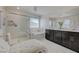 Modern bathroom with a glass enclosed shower, soaking tub, double vanity and white chaise lounge chair at 2940 Duverney Ave, Henderson, NV 89044