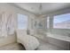 Bright bathroom with a glass enclosed shower, soaking tub and white chaise lounge chair and luxury bathrobes at 2940 Duverney Ave, Henderson, NV 89044