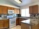 Well-lit kitchen with white appliances, wood cabinetry, and granite countertops at 4021 Broadriver Dr, Las Vegas, NV 89108