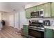 Modern kitchen boasting stainless steel appliances, green cabinets, and convenient access to other living areas at 4909 Desert Poppy Dr, Las Vegas, NV 89130