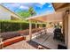 Covered patio featuring a built-in grill, four chairs, rock landscaping and a privacy fence at 4909 Desert Poppy Dr, Las Vegas, NV 89130
