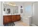 Well-lit bathroom features wood cabinets, tub and shower and tiled floors at 4916 White Jade St, North Las Vegas, NV 89081