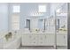 Bright bathroom featuring double sinks, a large mirror, and a soaking tub with stylish fixtures at 5108 Molveno Ct, Las Vegas, NV 89130