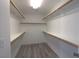 Walk-in closet with white walls, luxury vinyl plank flooring and wooden shelving to provide ample storage at 6042 Thorne Bay Ct, Las Vegas, NV 89110