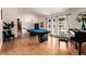 Spacious living room with hardwood floors, a pool table, and large windows that bring in natural light at 7384 Valhalla Ln, Las Vegas, NV 89123