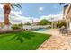 Inviting backyard oasis with a sparkling pool, lush artificial lawn, and covered patio seating area at 7384 Valhalla Ln, Las Vegas, NV 89123