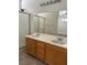 Bathroom featuring dual sinks, wood cabinets, granite counters, and a glass shower at 8756 Shady Pines Dr, Las Vegas, NV 89143