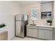 This kitchenette features a stainless steel refrigerator, white cabinets, and a microwave for a modern look at 9351 Aria Ridge Ave, Las Vegas, NV 89143